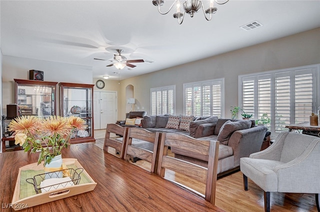 living room featuring ceiling fan with notable chandelier and light wood-type flooring