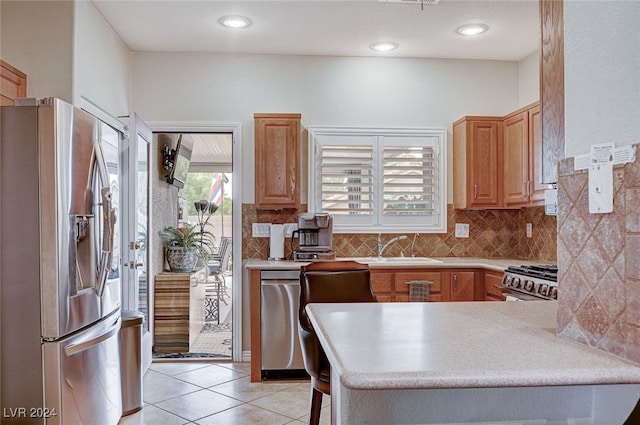 kitchen with kitchen peninsula, tasteful backsplash, stainless steel appliances, sink, and light tile patterned floors