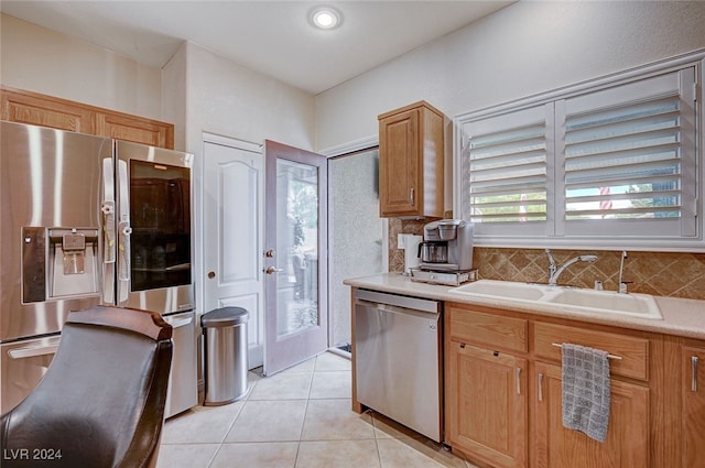 kitchen with backsplash, sink, light tile patterned floors, and stainless steel appliances