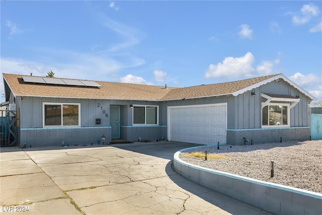 single story home featuring solar panels and a garage