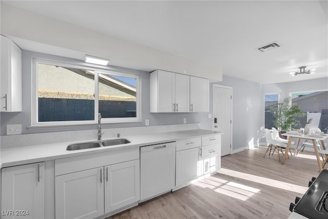 kitchen with white dishwasher, white cabinets, sink, and light hardwood / wood-style flooring