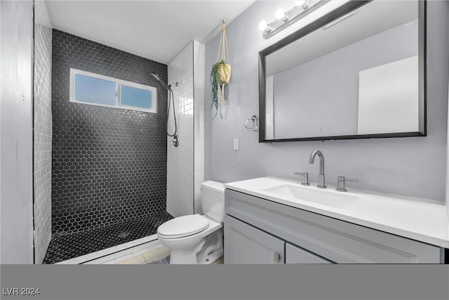 bathroom with tile patterned flooring, vanity, toilet, and a tile shower