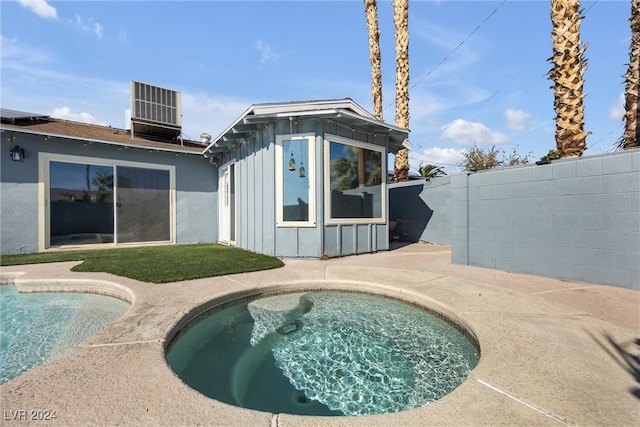 exterior space featuring central AC unit and a pool with hot tub