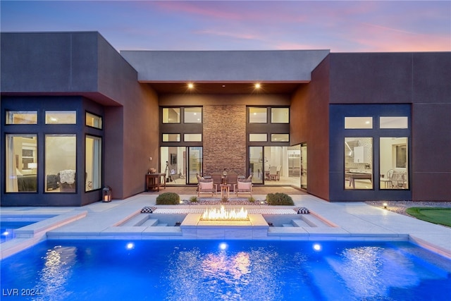 pool at dusk featuring an in ground hot tub, a patio, and a fire pit