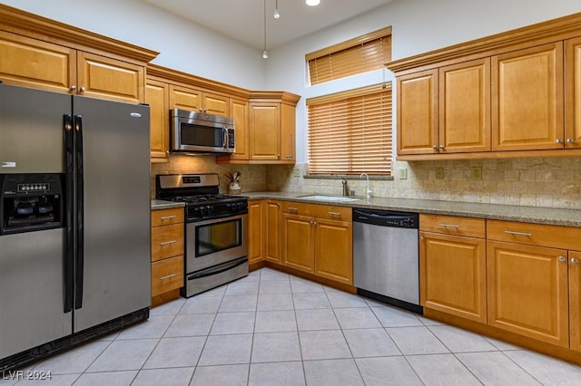 kitchen featuring sink, decorative backsplash, light stone countertops, and appliances with stainless steel finishes