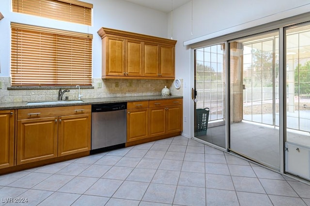 kitchen with light tile patterned flooring, tasteful backsplash, sink, stainless steel dishwasher, and light stone counters