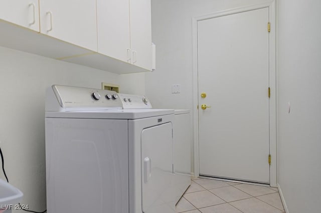 laundry room featuring cabinets, light tile patterned flooring, and separate washer and dryer