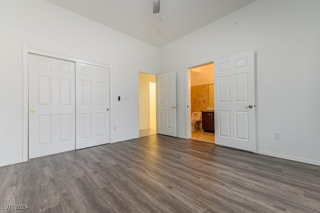 unfurnished bedroom featuring ceiling fan, dark hardwood / wood-style floors, ensuite bath, and a closet