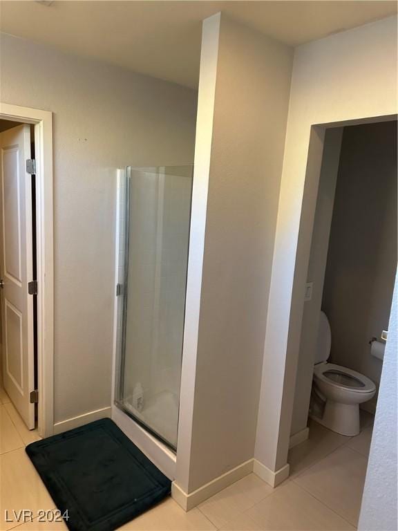 bathroom featuring tile patterned flooring, an enclosed shower, and toilet