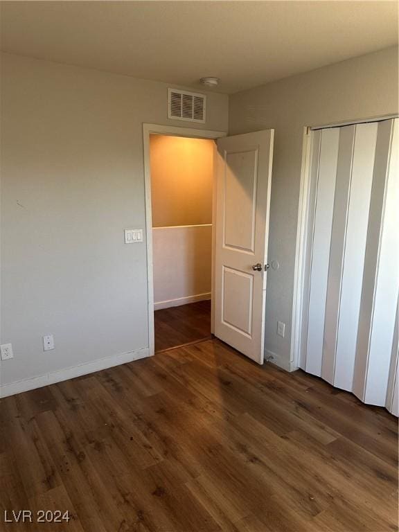 unfurnished bedroom featuring a closet and dark wood-type flooring