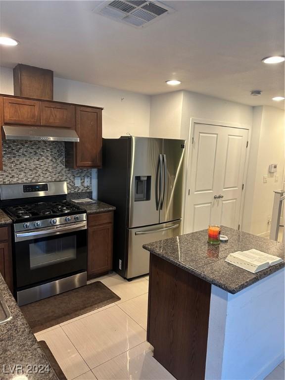 kitchen featuring tasteful backsplash, light tile patterned flooring, dark stone counters, and stainless steel appliances