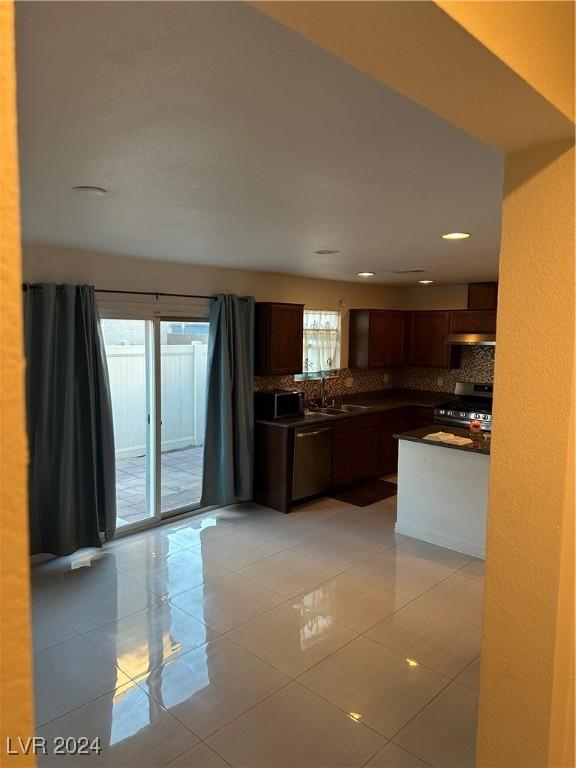 kitchen with backsplash, sink, light tile patterned flooring, and stainless steel appliances