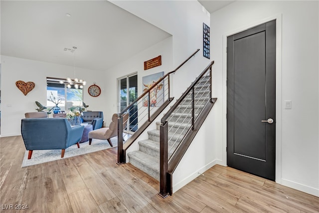 stairs with hardwood / wood-style floors and an inviting chandelier