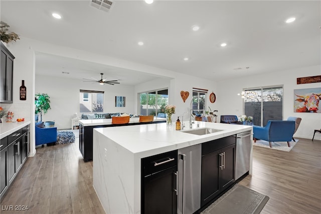 kitchen with ceiling fan, dishwasher, sink, light hardwood / wood-style floors, and a center island with sink