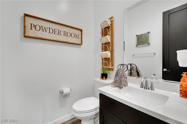 bathroom with hardwood / wood-style flooring, vanity, and toilet