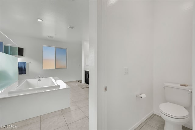 bathroom with tile patterned flooring, a bath, and toilet