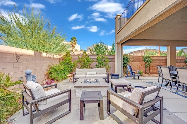 view of patio featuring a balcony and an outdoor living space with a fire pit