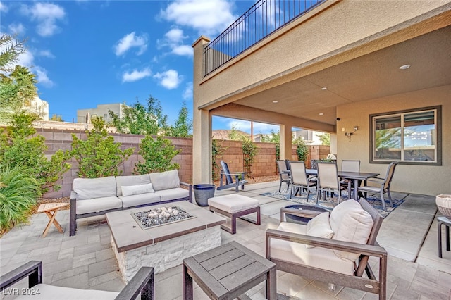 view of patio featuring a balcony and an outdoor living space with a fire pit