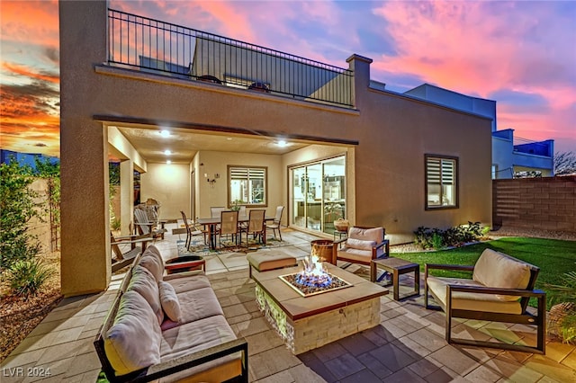 patio terrace at dusk with a balcony and an outdoor living space with a fire pit