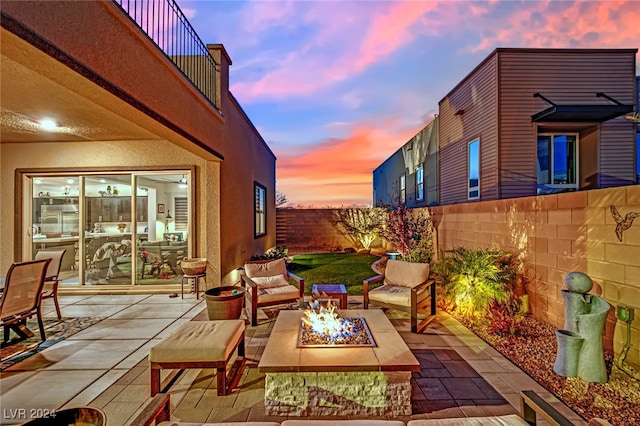 patio terrace at dusk featuring a balcony and an outdoor fire pit