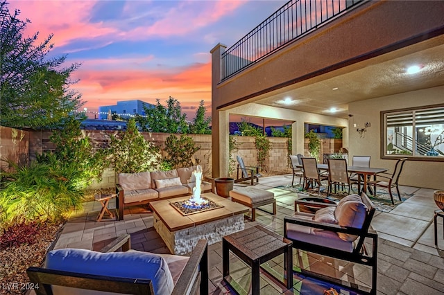 patio terrace at dusk with a balcony and an outdoor living space with a fire pit