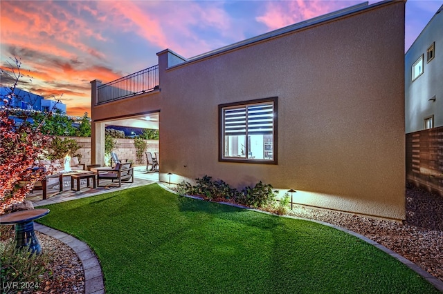 yard at dusk with a patio area, a balcony, and an outdoor hangout area