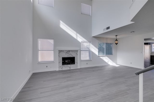 unfurnished living room with hardwood / wood-style flooring, a towering ceiling, and a premium fireplace