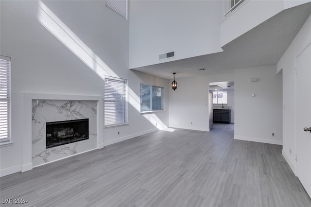 unfurnished living room with hardwood / wood-style flooring, a towering ceiling, and a fireplace