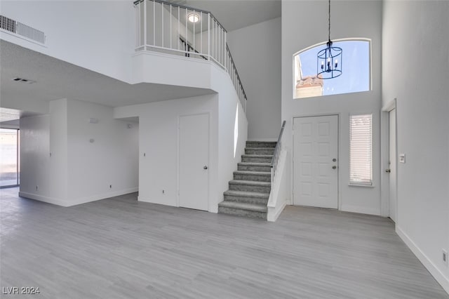 foyer entrance featuring an inviting chandelier, a healthy amount of sunlight, light hardwood / wood-style flooring, and a high ceiling