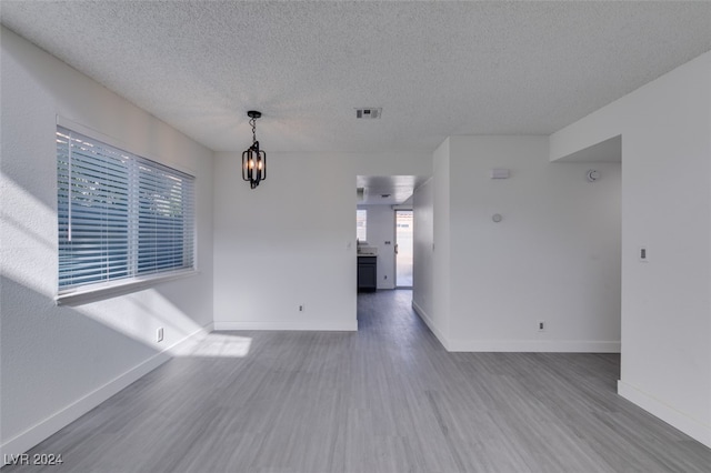 spare room featuring hardwood / wood-style flooring, a textured ceiling, and a notable chandelier