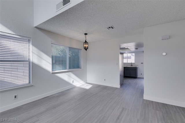 unfurnished room with an inviting chandelier, hardwood / wood-style floors, and a textured ceiling