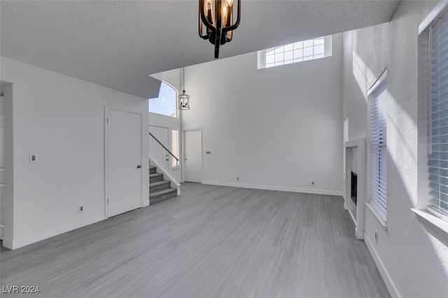 unfurnished living room with hardwood / wood-style flooring, a textured ceiling, and a high ceiling