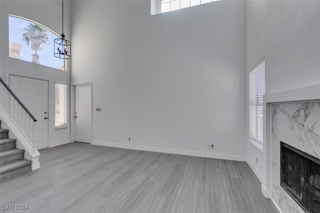 entryway featuring a high ceiling, plenty of natural light, a high end fireplace, and light hardwood / wood-style floors