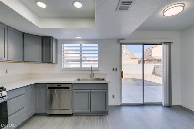 kitchen featuring sink, a textured ceiling, appliances with stainless steel finishes, gray cabinets, and light hardwood / wood-style floors