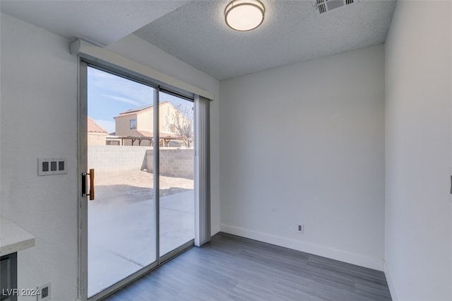 unfurnished room with wood-type flooring and a textured ceiling