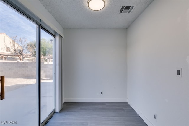 spare room featuring dark wood-type flooring and a textured ceiling