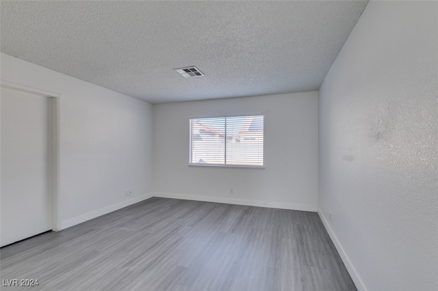 unfurnished room with light hardwood / wood-style floors and a textured ceiling