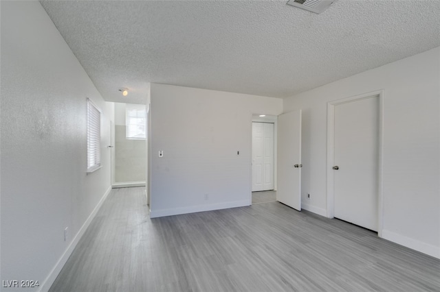 unfurnished room with a textured ceiling and light wood-type flooring