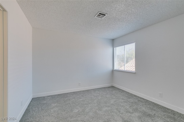 carpeted spare room featuring a textured ceiling