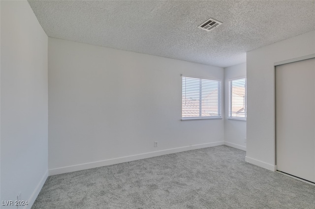 unfurnished bedroom with light colored carpet, a textured ceiling, and a closet