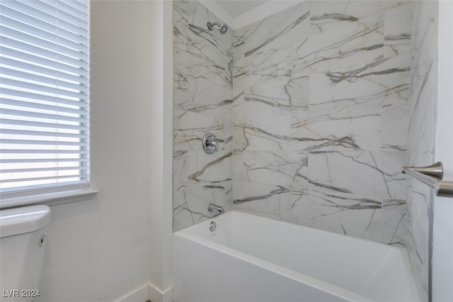 bathroom with tiled shower / bath combo and toilet