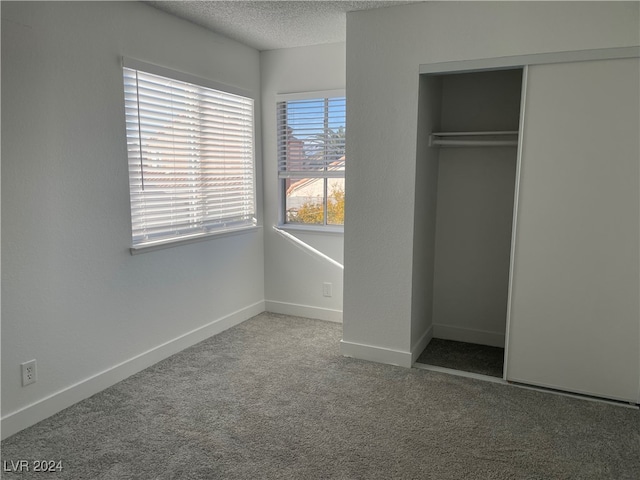 unfurnished bedroom with carpet floors, a closet, and a textured ceiling