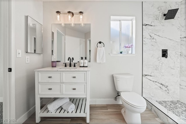 bathroom featuring tiled shower, hardwood / wood-style floors, vanity, and toilet