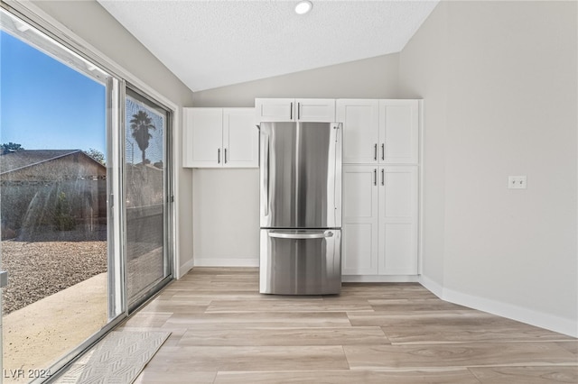 kitchen featuring white cabinets, stainless steel fridge, lofted ceiling, and a textured ceiling