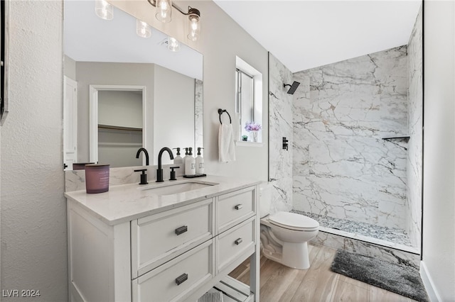 bathroom with a tile shower, toilet, vanity, and hardwood / wood-style flooring