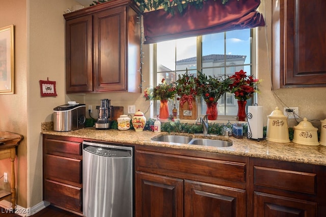 kitchen featuring dishwasher, light stone counters, and sink