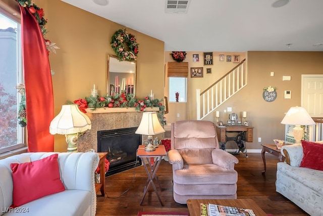 living room with a tile fireplace and dark wood-type flooring