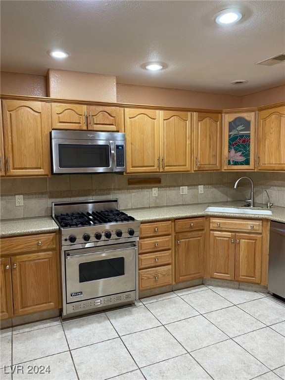 kitchen with decorative backsplash, sink, light tile patterned floors, and appliances with stainless steel finishes