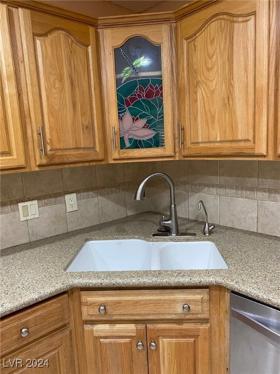 kitchen featuring dishwasher, tasteful backsplash, light stone counters, and sink