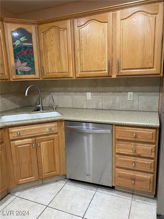 kitchen featuring tasteful backsplash, dishwasher, light tile patterned floors, and sink